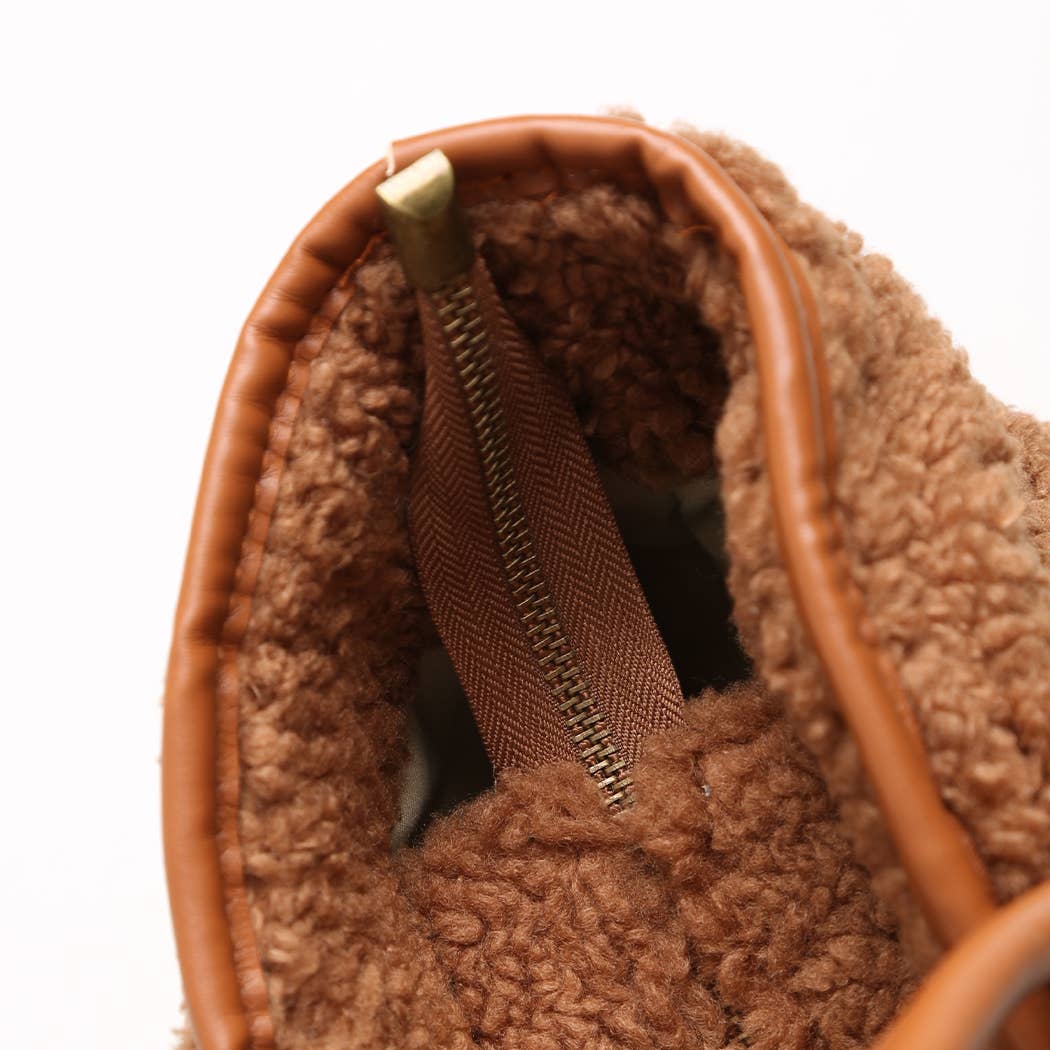 Close-up of a brown fuzzy bag with a gold zipper on a white background