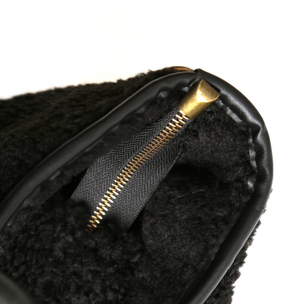 Close-up of a black earbud with gold zipper detail on a white background