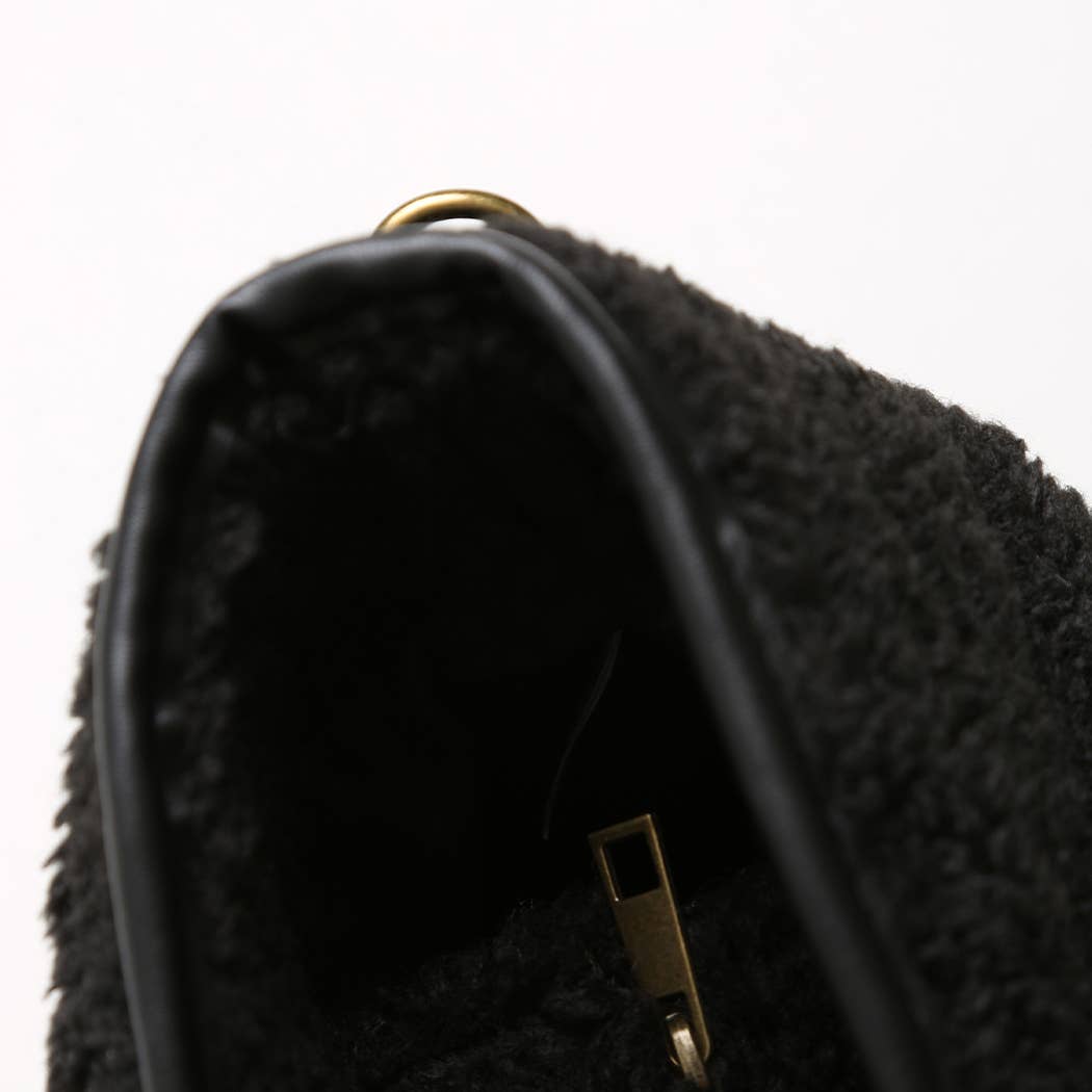 Close-up of a textured black shoe with a gold buckle on a white background