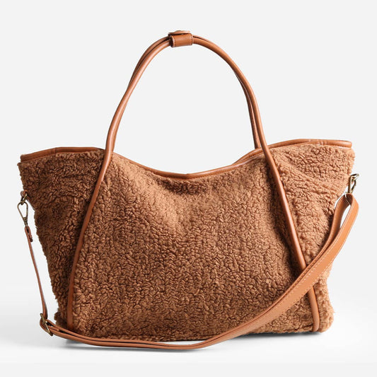 Brown textured handbag with leather handles and strap on a light gray background