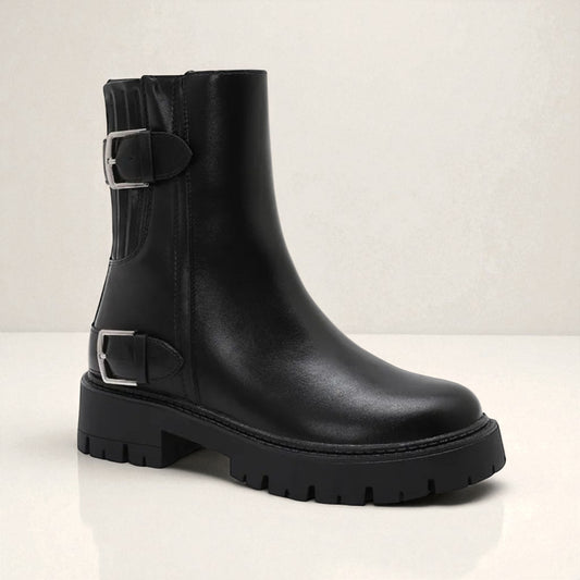Black leather boot with buckles on a light gray background